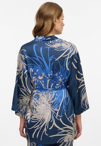 Accappatoio satinado blu navy con motivo floreale blu e oro, maniche lunghe, vita con cintura, texture liscia e vestibilità rilassata.