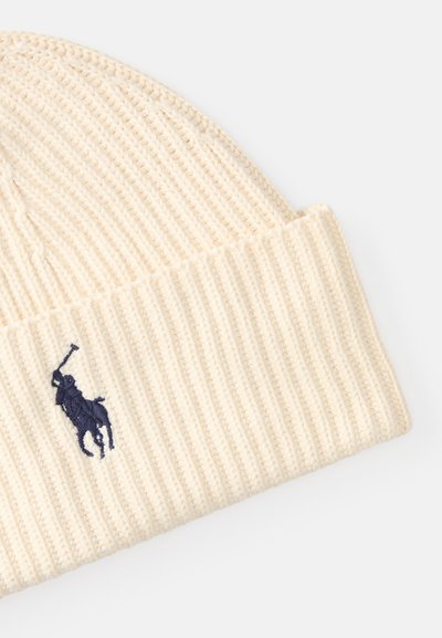 Gorro de malha creme com textura canelada e bainha dobrada. Apresenta um logótipo de cavalo bordado em azul marinho de um dos lados.