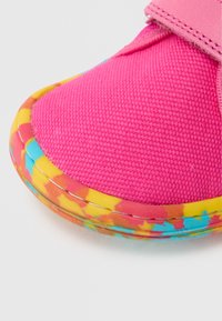 Lapse kinga, millel on hele roosa tekstiilist pealmine osa ja mitmevärviline kummist tald kollase, oranži ja sinise lääsitriipudega. Kinnitub VELCRO takjakinnitusega.