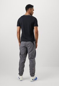 Men's dark gray T-shirt with a round neckline, paired with lightweight gray pants featuring black side panels and elastic cuffs at the ankles.