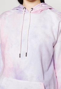 Hoodie w pastelowym fioletowym i różowym wzorze tie-dye, z kapturem na sznurku i teksturowanym materiałem, posiadający kieszeń z przodu.