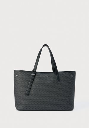 Bolso tote negro de Michael Kors con un estampado de monogramas repetidos, dos asas para el hombro y una correa ajustable con hebilla, sobre un fondo claro.