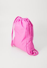 Sac à dos en rose fait de tissu léger, comportant un haut froncé, des sangles en cordon pour les épaules et une texture lisse et brillante.