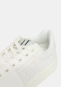Sneaker bianco realizzato in materiale sintetico liscio, con una patch logo testurizzata, lacci tondi e una suola in gomma a profilo basso.