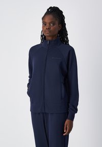 Giacca zip-up blu navy realizzata in tessuto morbido, con colletto alto, tasche laterali e polsini a costine per il massimo comfort.