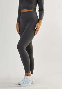 Graue Leggings und ein passendes langärmeliges Oberteil aus dehnbarem Stoff. Die Leggings verfügen über ein strukturiertes Paneeldesign und einen hohen Taillenbund.