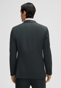 Giacca da uomo grigia scura con una texture liscia, design a un solo petto, rever a punta e polsini abbottonati. Vista posteriore pulita senza motivi visibili.