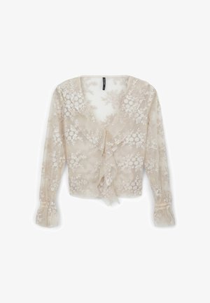 Chemisier beige transparent avec broderie florale, décolleté en V, devant volanté, manches longues avec poignets froncés, tissu léger et détails délicats.