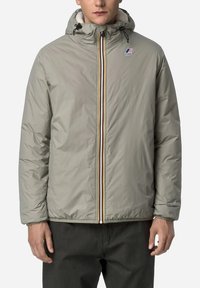 Giacca imbottita grigia chiara con cappuccio, zip frontale con una striscia colorata e un logo ricamato sul petto. Polsini elasticizzati.