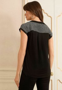 Schwarzes Kurzarmoberteil mit grauem strukturiertem Oberteil, runder Ausschnitt und lockerer Passform. Glattes Material mit dezenter Schattierung.