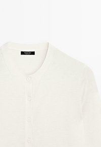 Cardigan bianco con collo rotondo e chiusura a bottoni, con un'etichetta che riporta "Massimo Dutti." Texture morbida e lavorata a maglia.
