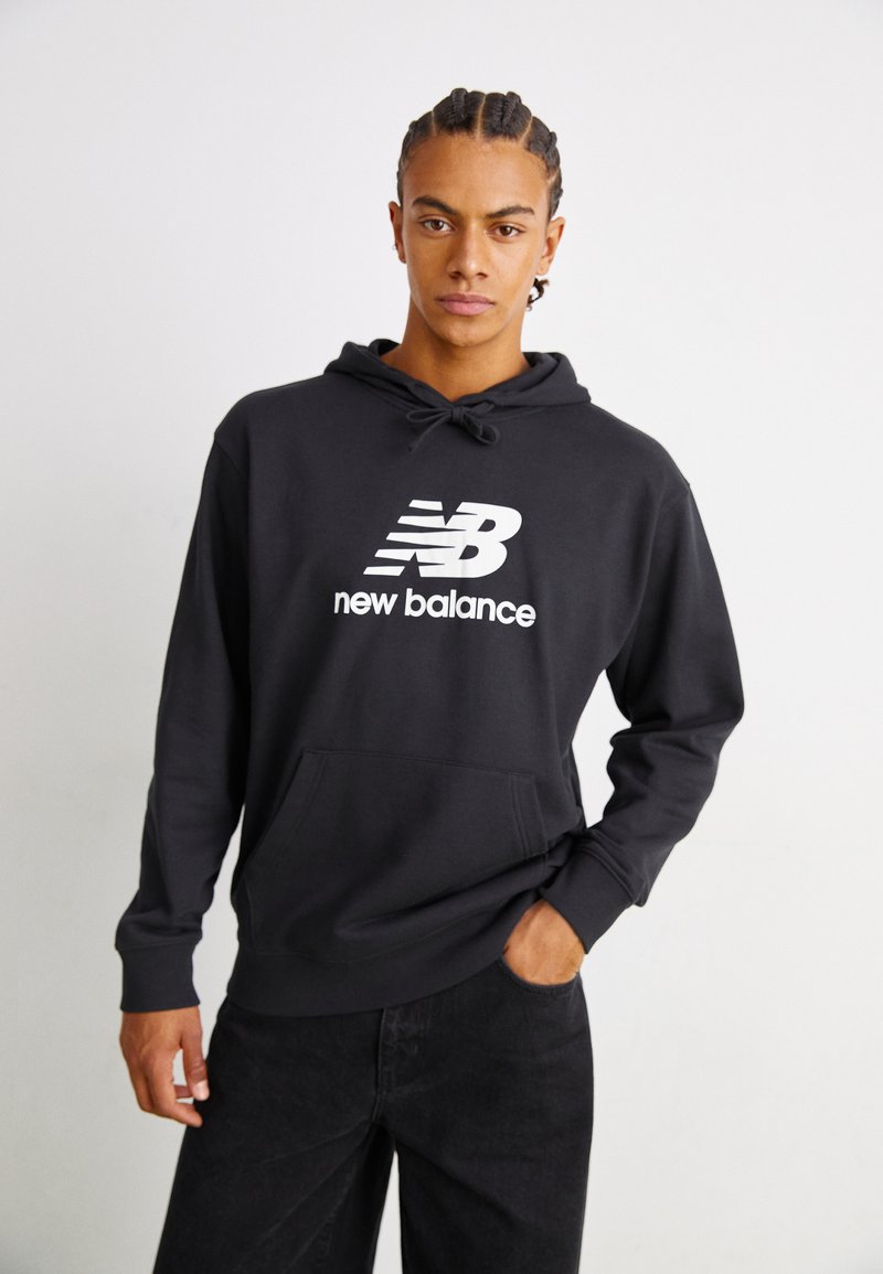 Fekete kapucnis pulóver kenguru zsebbel és húzózsinórral. Elöl található egy nagy fehér "New Balance" logó. Sima szövettextúra.