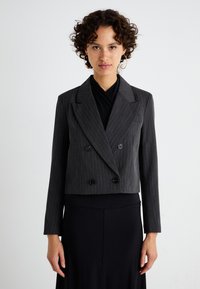 Harmaassa pinstripe-kankaassa valmistettu kaksirivinen lyhyt takki. Ominaisuuksina leveät kaulukset, kaksi etupainiketta ja pitkät hihat.