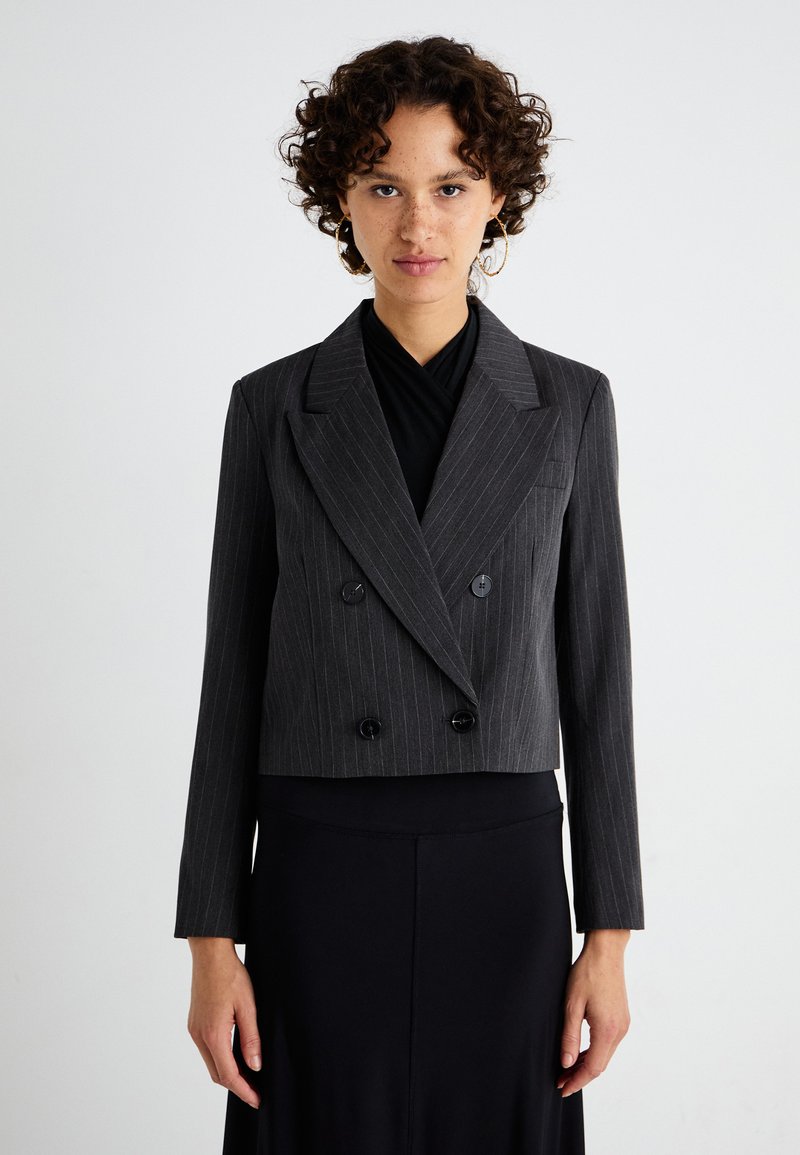Harmaassa pinstripe-kankaassa valmistettu kaksirivinen lyhyt takki. Ominaisuuksina leveät kaulukset, kaksi etupainiketta ja pitkät hihat.