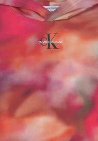 Mikina s vázáním v odstínech červené, oranžové a růžové s černým logem "CK" a bílým logem "Calvin Klein Jeans" umístěným centrálně pod kapucí.