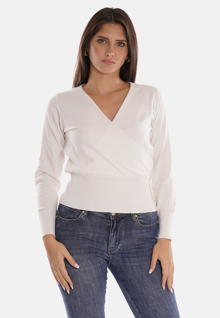 Maglione avvolgente bianco con maniche lunghe e orlo a coste, realizzato in materiale morbido, abbinato a jeans blu scuro. Il modello posa su uno sfondo neutro.