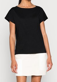 Camiseta negra de manga corta con escote redondo, hecha de un tejido suave, combinada con una falda de color claro con bolsillos tipo parche.