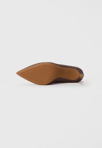 Escarpin marron pour femmes avec une tige texturée, bout pointu et une semelle en caoutchouc beige présentant un motif géométrique. Talon fin pour une élégance accrue.