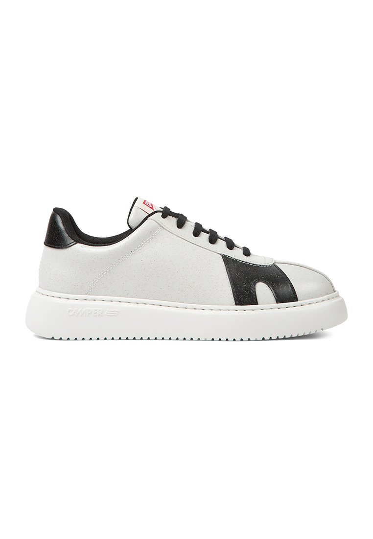Zapatilla de deporte de cuero blanco con un acento de cuero negro, puntera redonda, superficie texturizada, suela en contraste y cordones negros. Logo en el lateral.