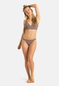 Brun rippad bikiniuppsättning med triangulär bralette och lågröstande byxor, utformad med justerbara remmar och minimalistisk stil.