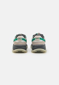 Multicolored sneakers featuring a beige suede upper, grey accents, and green straps, with a textured rubber sole and pull tab.
