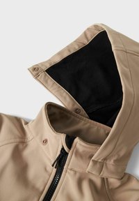 Beige Kapuzenjacke mit schwarzem Fleece-Innenfutter, ausgestattet mit einem Reißverschluss und Druckknöpfen. Glattes Material mit strukturiertem Schnitt und hohem Kragen.