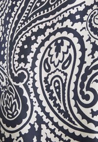 Motif paisley complexe en noir et blanc avec des formes florales et en goutte sur la surface du tissu.