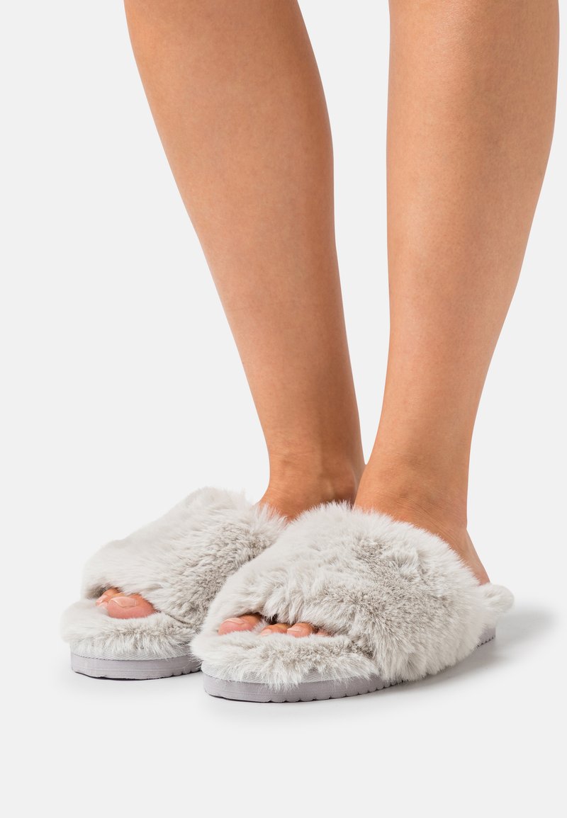 Grey fluffy slide slippers with an open toe design, soft texture, and a thick sole, providing comfort and warmth.