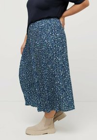 Blommig maxikjol i marinblått med plisserad design. Har små gröna och vita mönster, elastisk midja och når under vadmuskeln.