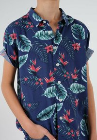 Kortærmet skjorte i navy stof med livlige grønne blade og røde blomster. Har knaplukning og optrukne manchetter. Blød tekstur, afslappet design.