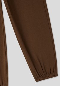 Brązowe dresowe spodnie z bawełny z elastycznymi mankietami; miękka tekstura, zwężający się krój i bezszwowa konstrukcja.