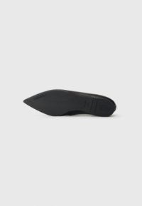 Chaussure noire à bout pointu avec un design élégant, une texture lisse et un talon fin. La semelle présente un branding subtil et un avant plat.