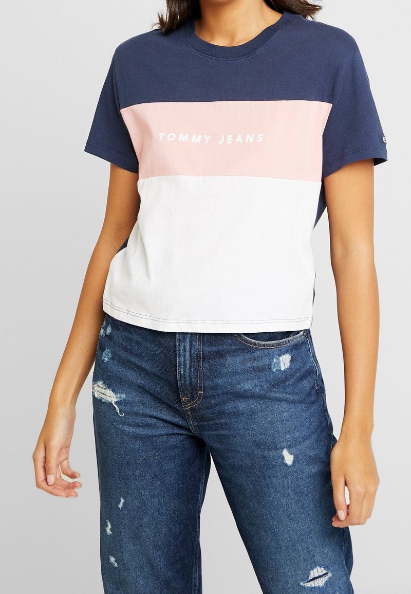 Cropped t-shirt navy, rosa e bianco con maniche corte, caratterizzato dal logo "TOMMY JEANS" sul petto, realizzato in morbido materiale di cotone.