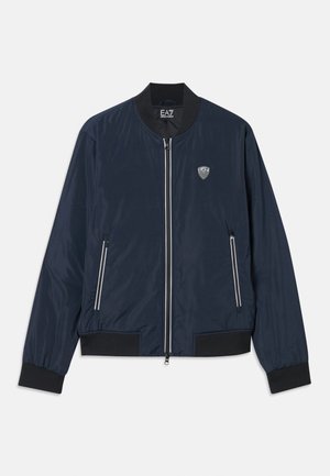 Veste bombardier bleu marine en nylon lisse. Dotée d'une fermeture éclair à l'avant, de poignets et d'un ourlet côtelés, de poches latérales et d'un petit logo sur la poitrine.