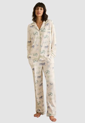 Pajama set in cream fabric featuring animal prints. Includes long-sleeved button-up top and matching pants with an elastic waistband.