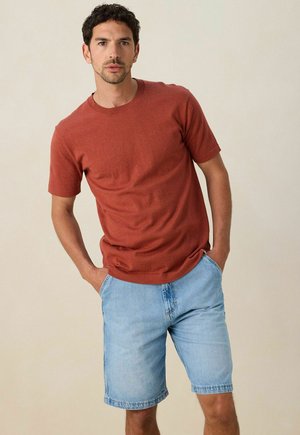 Roestkleurig katoenen T-shirt met korte mouwen, gecombineerd met lichtblauwe denim korte broeken; casual pasvorm, met zichtbare stiksels en zijzakken.