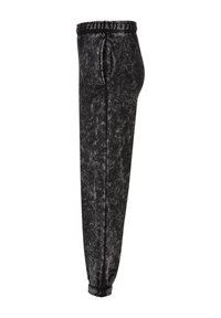 Sorte, teksturerte joggebukser med elastisk midje og innsnevret ben. Stoffet har et subtilt marmorert mønster som forsterker den visuelle dybden.