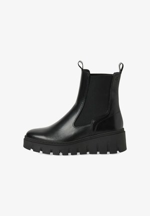 Botas negras hasta el tobillo con un exterior de cuero suave, paneles laterales elásticos y una suela gruesa con tacos. Presentan tiradores para facilitar el calzado.