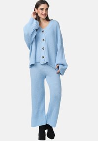 Ensemble en maille côtelée bleu clair comprenant un pull à col en V, des manches longues, de grands boutons et un pantalon large à coupe décontractée.