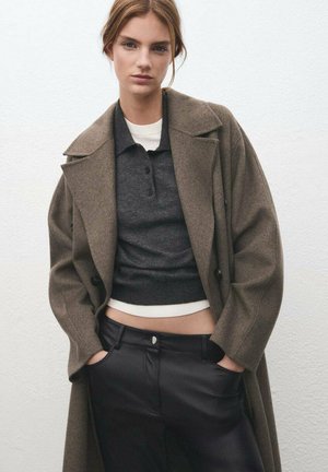 Brown wool coat with large lapels over a dark gray top; black leather pants with front pockets; smooth textures and tailored fit.