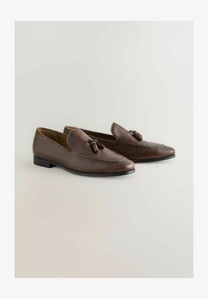 Barna bőrből készült mokaszinok texturált mintázattal, díszítő bojtokkal. Alacsony sarok és lekerekített orr kialakítás. Letisztult belső bélés.