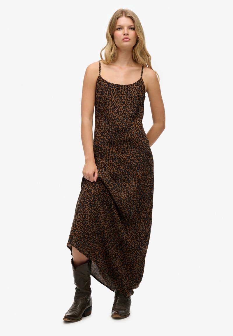 Leopardprint maxi kjole i brun og sort, med tynde stropper og en flødende silhuet, parret med mørke, knæhøje støvler.