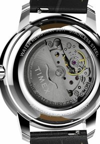 Timex Waterbury watch with stainless steel case, automatic movement, black leather strap, and visible mechanical components. Water-resistant to 50m.