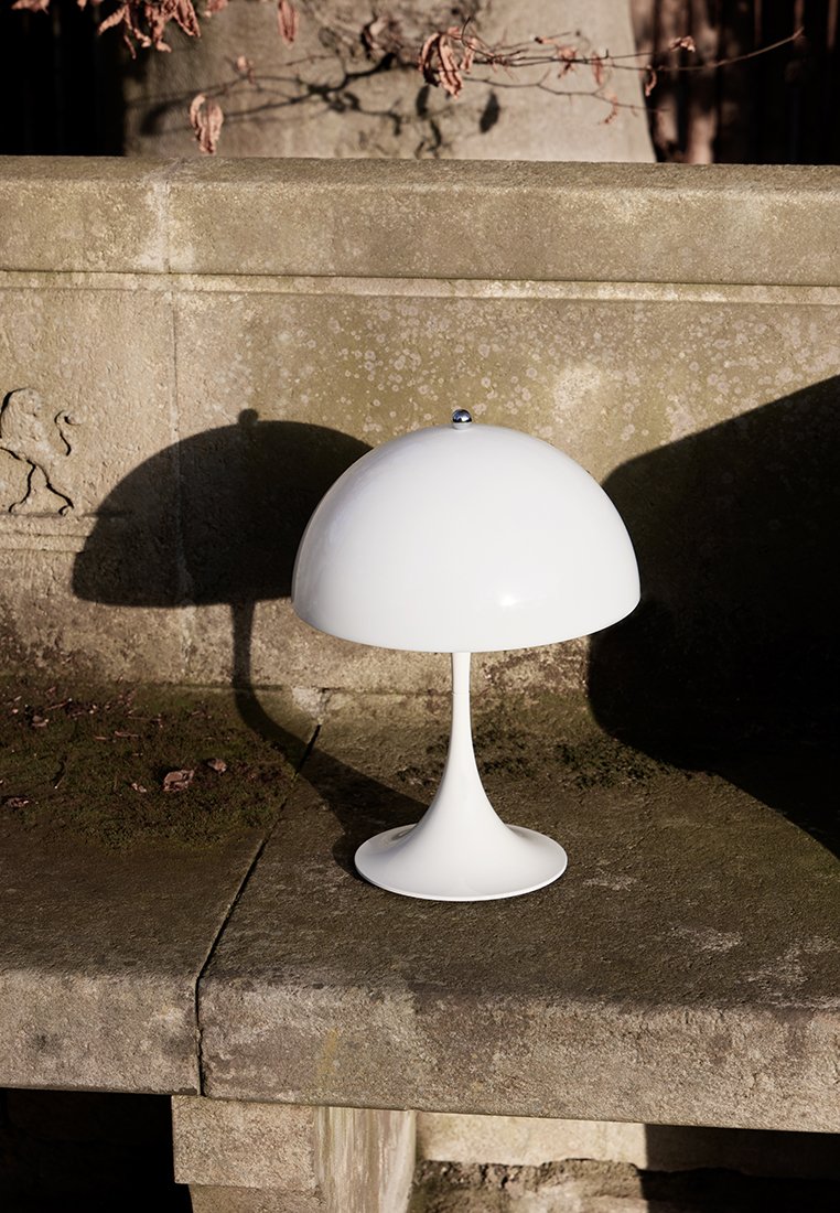 Weiße pilzförmige Tischlampe mit glänzender Oberfläche, schmalem Stiel und runder Basis. Sie verfügt über einen verchromten Knopf oben.
