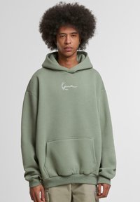 Light green hoodie made of soft fabric, featuring a front pocket and a white logo on the chest. Loose fit with ribbed cuffs and hem.