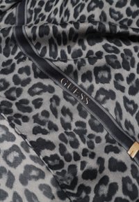 Sciarpa in seta con motivo a stampa leopardata grigia e nera e bordo nero, caratterizzata dalla scritta dorata "GUESS".