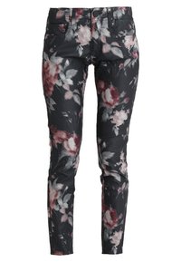 Jean skinny à imprimé floral noir avec des fleurs roses et blanches. Fabrication en tissu extensible, avec cinq poches et une fermeture éclair.