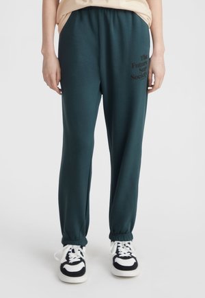 Donkergroene joggers met elastische tailleband en opgerolde enkels, voorzien van de bedrukte tekst "The Future Sur Society" op het linkerbeen. Glad stoftextuur.