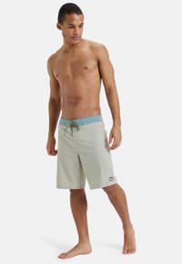 Svetlosivé plavky s modrým elastickým pásom, vybavené šnúrkou a malou logom nášivkou na spodnom leme.