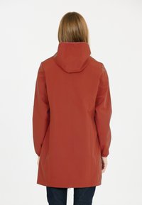 Vesiohjaa, punaruskea takki hupulla, sileällä pinnalla, pitkät hihat ja hieman kapeneva siluetti, joka ulottuu puoliväliin reisiä.